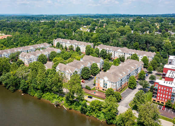 A river flows through a green forest and a residential area.