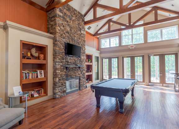 A room with a pool table and a stone fireplace.