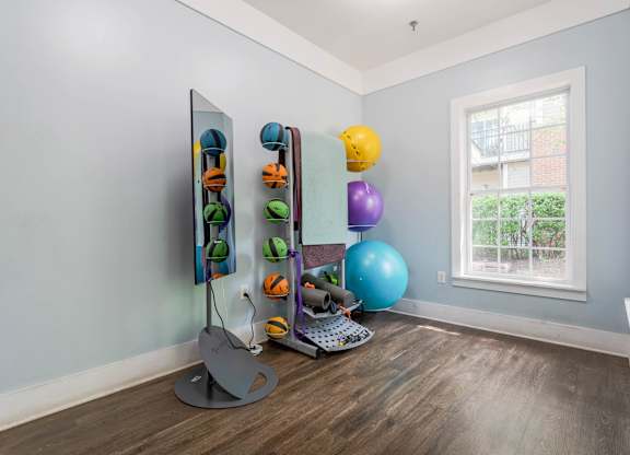 A room with a mirror, exercise balls, and a window.