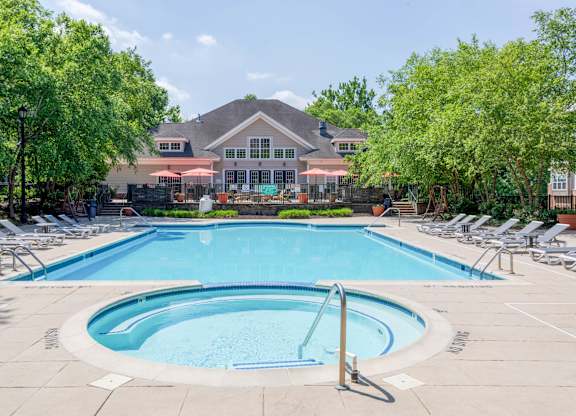 A large swimming pool surrounded by lounge chairs and trees.