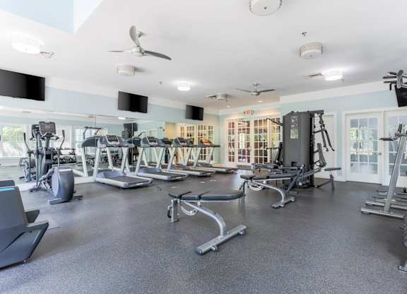 A spacious gym with a variety of equipment including treadmills, elliptical machines, and weight machines.