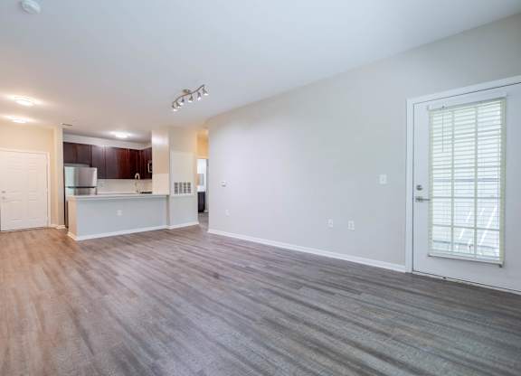 A spacious living room with a kitchen in the background.