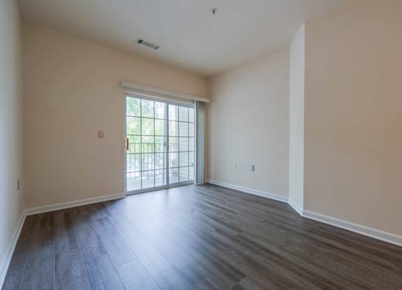 A room with a sliding glass door leading to a balcony.