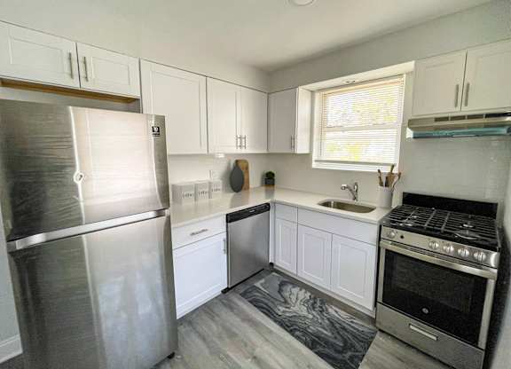 A kitchen with a stainless steel refrigerator and oven, white cabinets, and a marble floor.at Lawndale Apartments, Pennsylvania