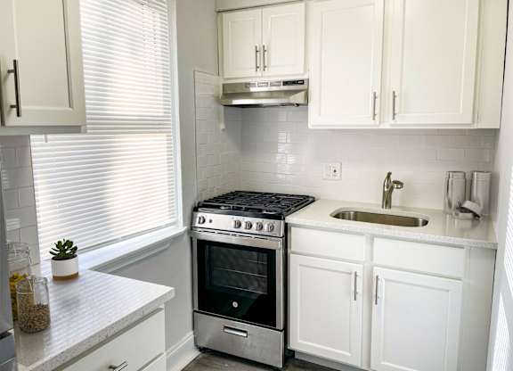 A modern kitchen with white cabinets and a stainless steel oven.at Lawndale Apartments, Philadelphia, PA