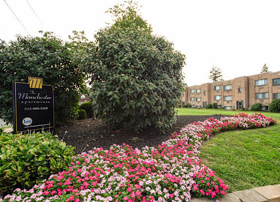 A sign for Manchester Apartments is in front of a flower bed in Philadelphia