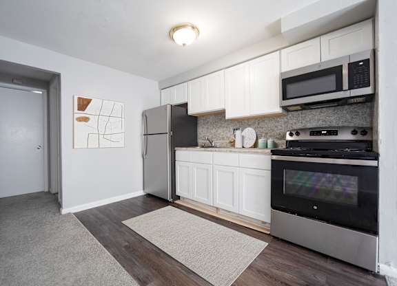 A kitchen with a refrigerator, oven, and microwave.