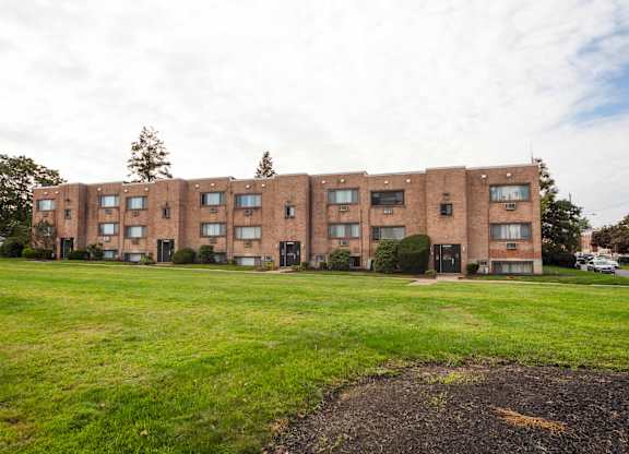 A large brick building with a green lawn in front at Manchester Apartments, Philadelphia