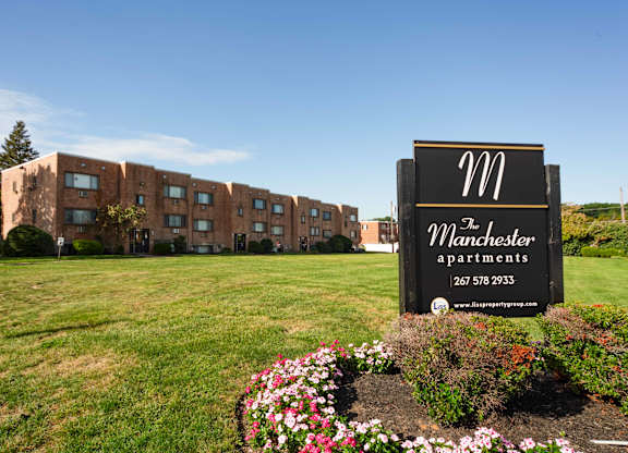 A sign for Manchester Apartments stands in front of a building in Philadelphia