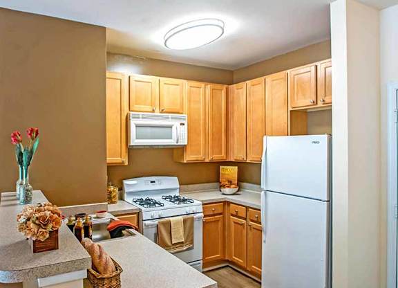 a kitchen with white appliances and wooden cabinets at Riverview Landing @ Valley Forge, Eagleville