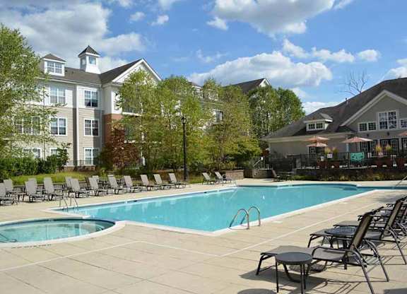 a swimming pool with chairs around it in front of a building at Riverview Landing @ Valley Forge, Eagleville Pennsylvania