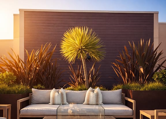 A modern outdoor seating area with a white couch and a fire pit.
