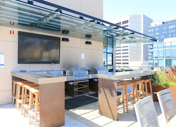 A modern outdoor kitchen with a bar area and seating.