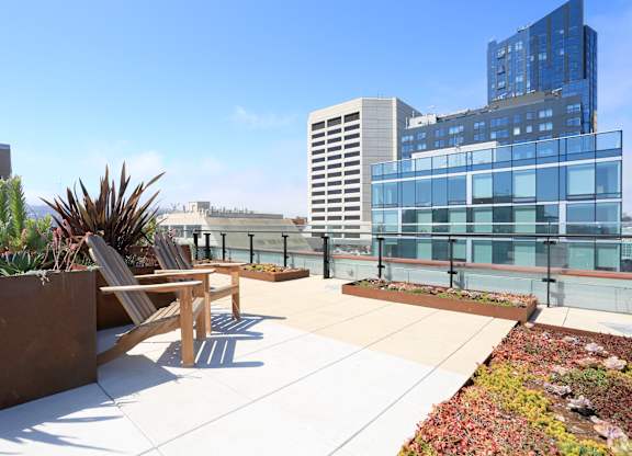 A rooftop patio with a table and chairs overlooking a cityscape.