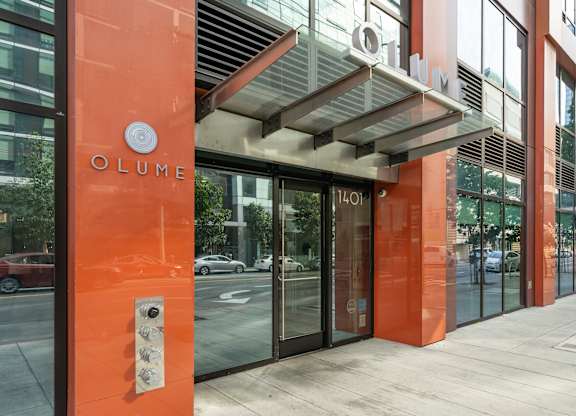 The entrance to a building with a glass door and a sign that reads "OLUME".