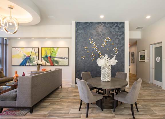 A grey couch sits in front of a grey and white wall with a painting on it.