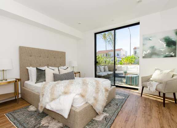 A bedroom with a large bed and a chair.