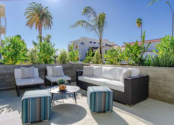A patio with a white couch, two chairs, and a coffee table.