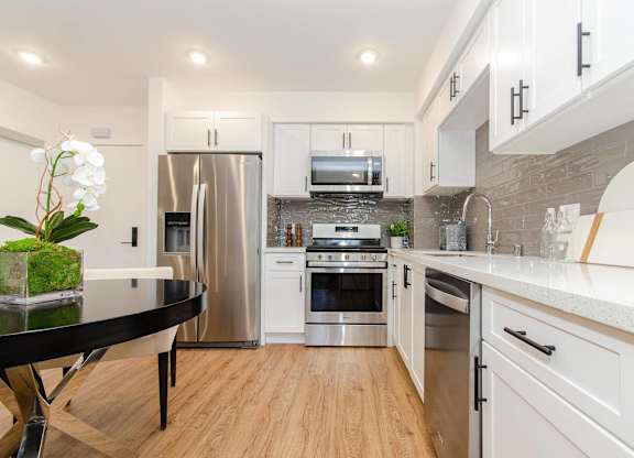 A modern kitchen with white cabinets and a black table.