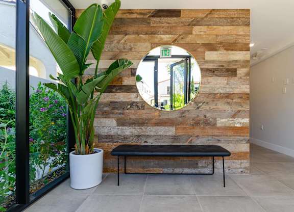 A round mirror hangs on a wooden wall above a bench.