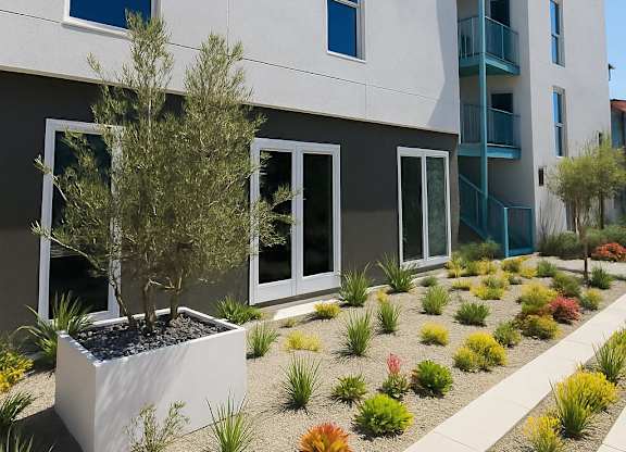 A white building with a blue balcony and a planter in front.