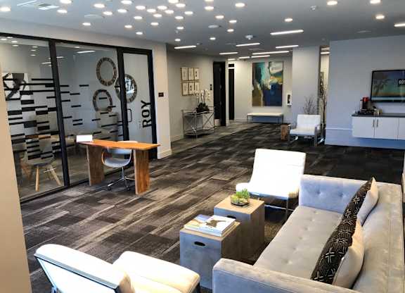 A modern community room with a grey couch and a wooden coffee table.