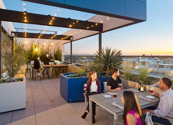 A group of people are sitting around a table on a rooftop patio.