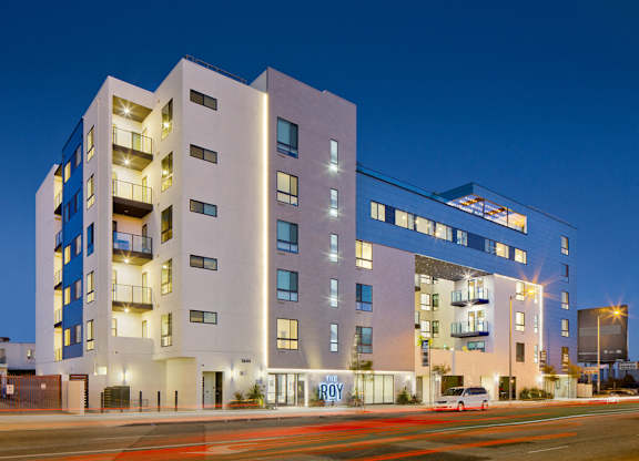 A image of The Roy apartment building with a lit up sign that says