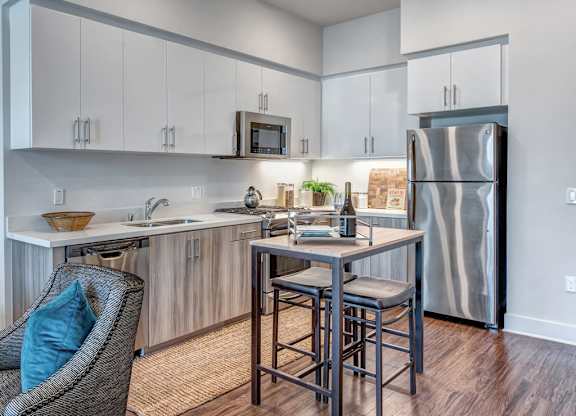 A kitchen with a refrigerator, sink, and bar stools.