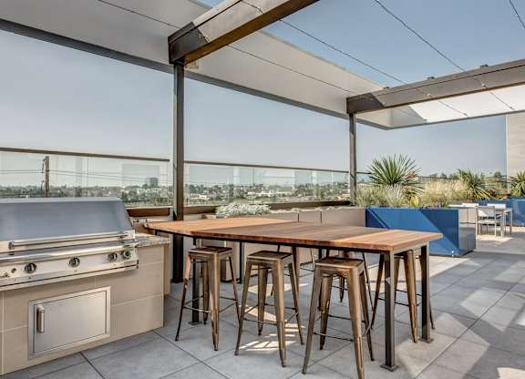 A modern outdoor kitchen with a grill and bar stools.