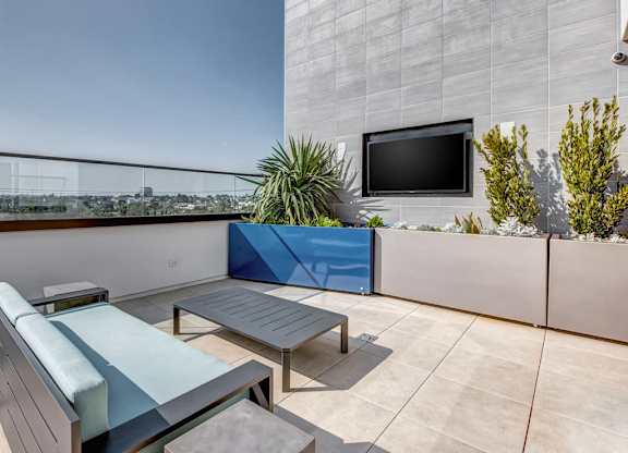 A modern balcony with a blue cushion and a flat screen TV.