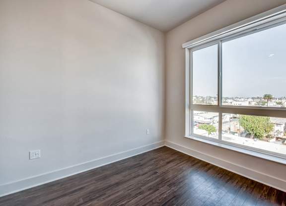 A room with a large window and wooden flooring.