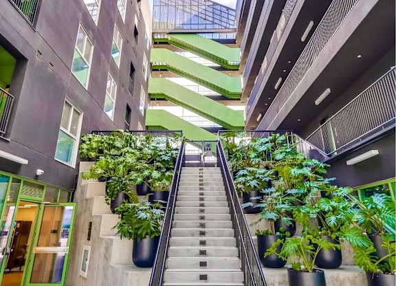 A staircase with a metal railing leads up to a brightly lit atrium.