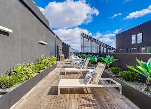 A modern balcony with wooden flooring and white lounge chairs.