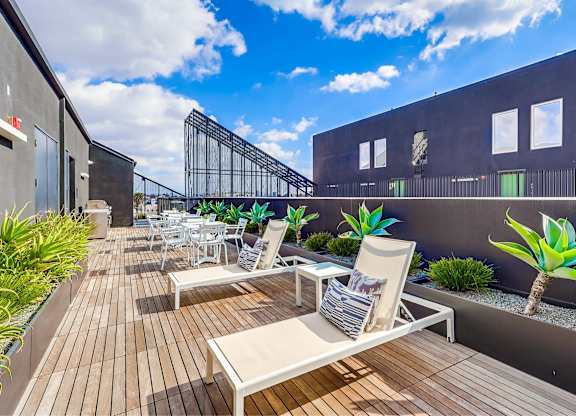 A patio with white chairs and a wooden table.