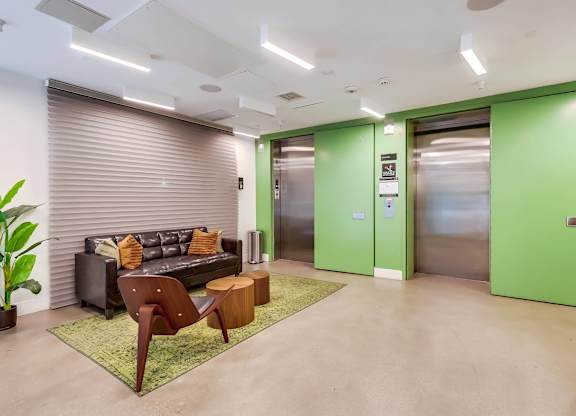 A modern office lobby with a green wall and a wooden chair.