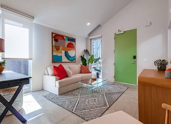 A modern living room with a white sofa and a large abstract painting on the wall.