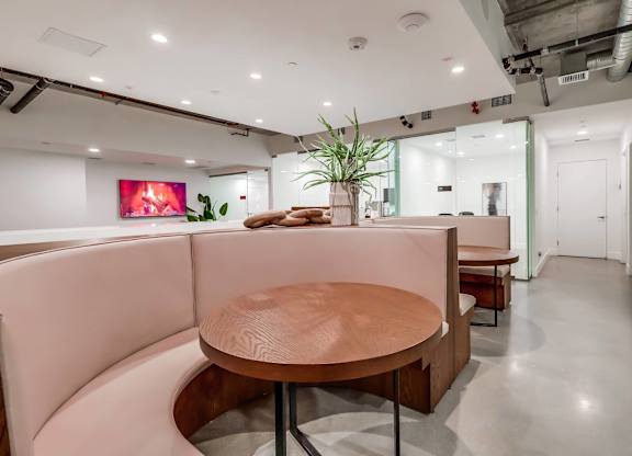 A modern office space with a wooden table and pink booths.