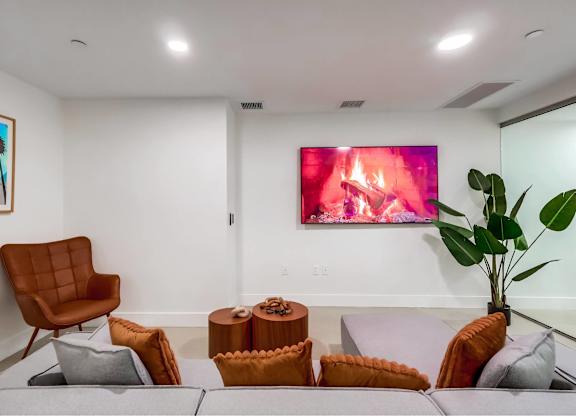 A living room with a brown chair, a grey couch, and a painting on the wall.