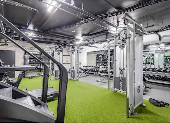 A gym with a green floor and various exercise equipment.