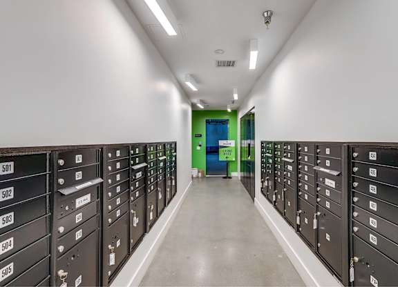 A long hallway with black filing cabinets on either side and a green door at the end.
