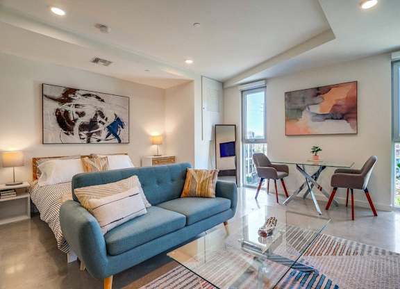 A living room with a blue couch and a glass table.
