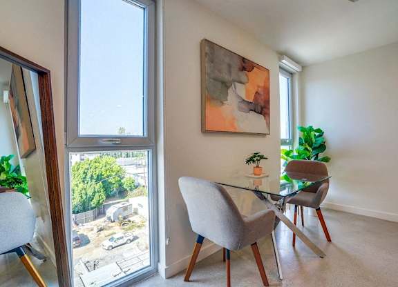 A room with a table and chairs and a painting on the wall.