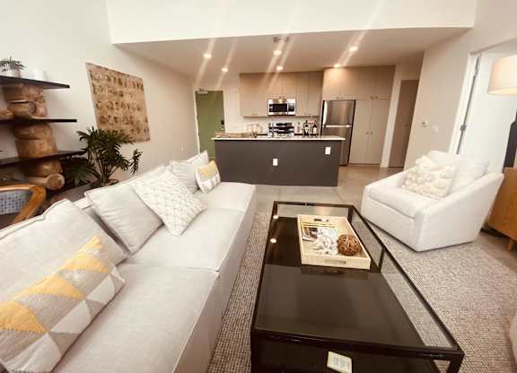 A modern living room with a white sofa and a glass coffee table.