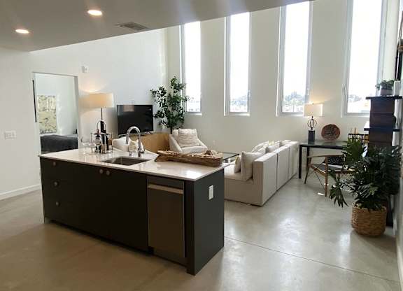 A modern kitchen with a large island and a couch in the background.