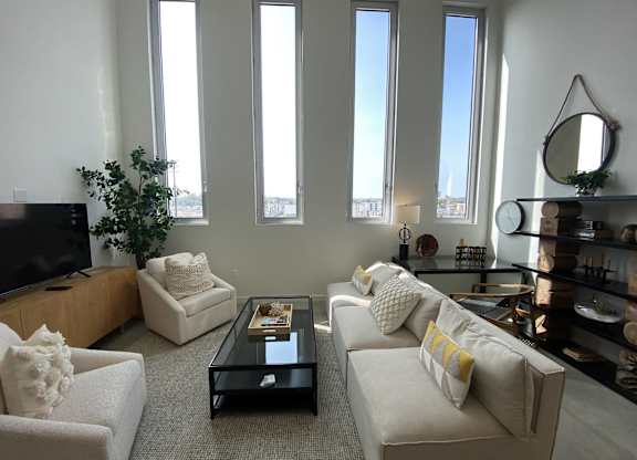 A living room with a white couch, a black coffee table, and a flat screen TV.