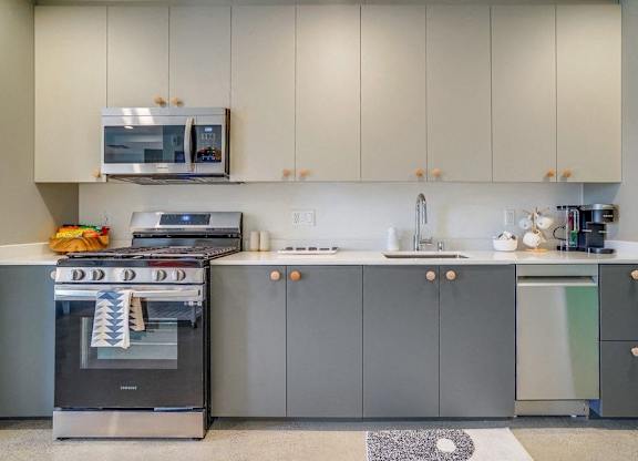 A modern kitchen with a stainless steel oven and grey cabinets.