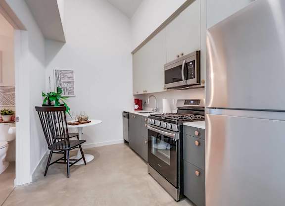 A kitchen with a black chair and a stainless steel refrigerator.