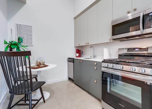 A modern kitchen with a black chair and a white table.