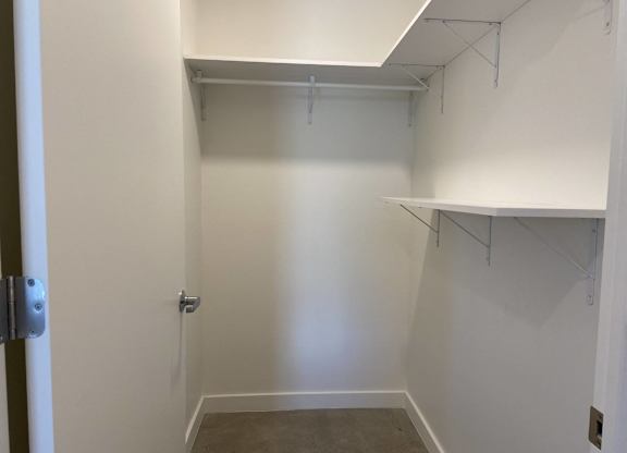 A white closet with a shelf and a door.